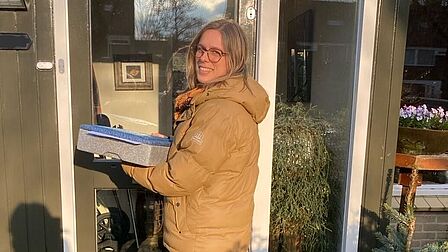 Wethouder Julie d'Hondt staat voor de deur van een inwoner om een maaltijd te bezorgen