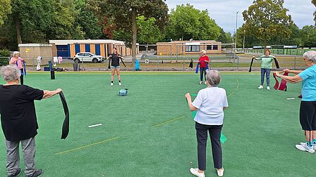 Groep sporters volgt sportles en oefent met elastieken op een sportveld